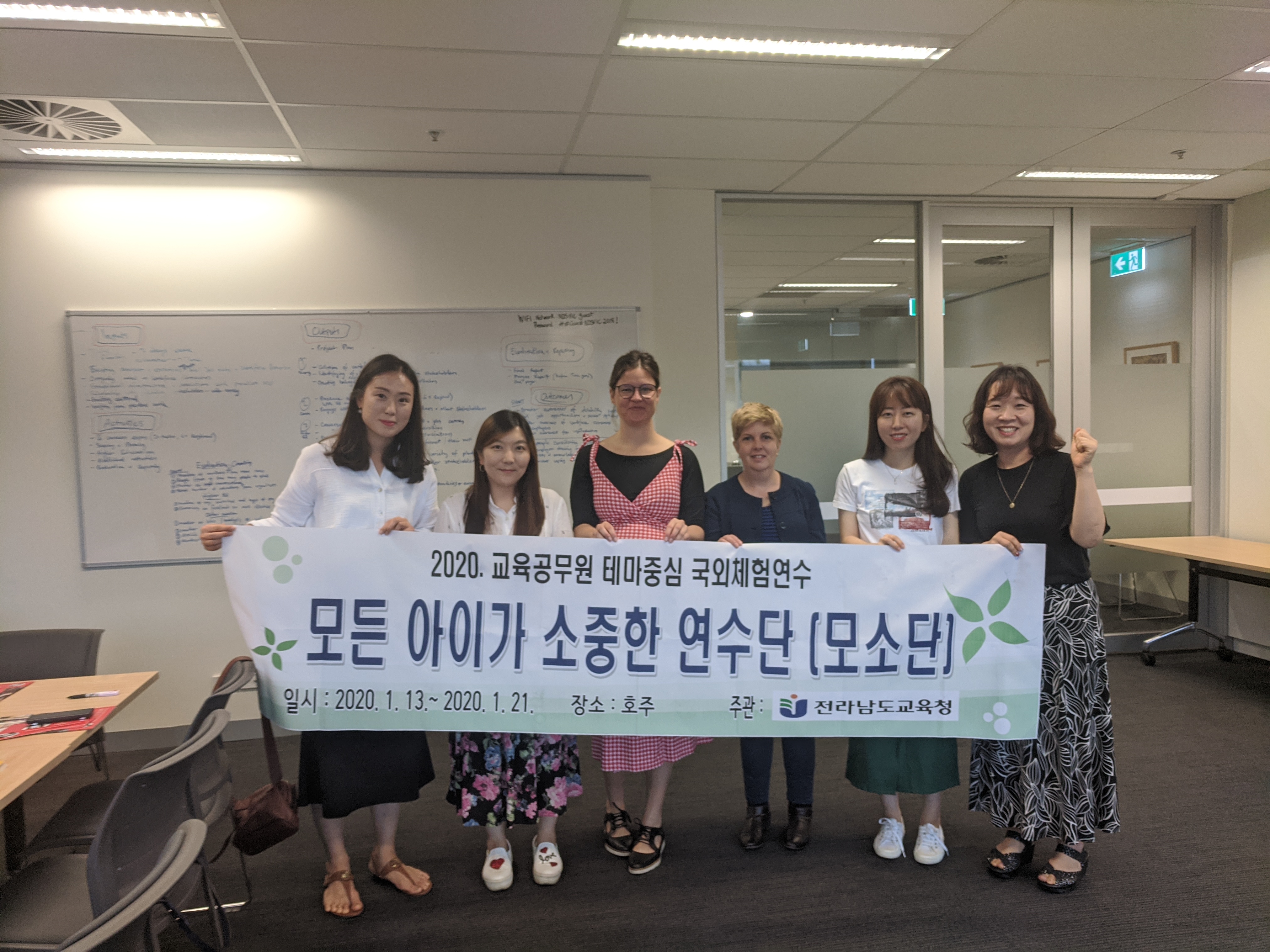 group of ladies holding a banner in Korean in a office